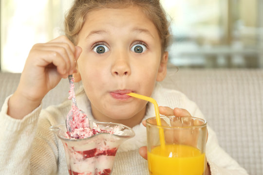 Cute little girl with ice-cream and juice in cafe, close up view