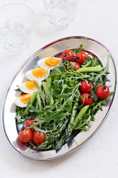 Asparagus salad with arugula, cherry tomatoes and eggs. Overhead view.