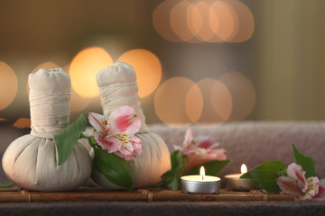 Beautiful spa composition with massage compress balls and candles on blurred background