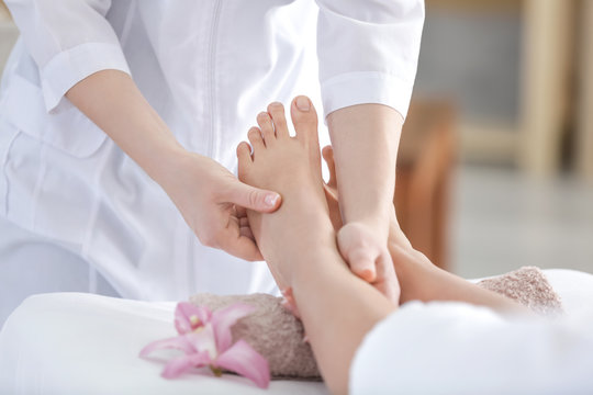 Female masseur massaging woman's foot in spa salon