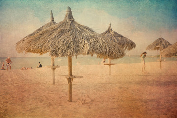 Vintage texture style view of tropical beach with grass hut palapas