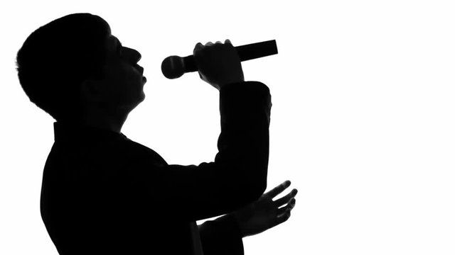 silhouette video of a concert of a man emotionally singing with a microphone