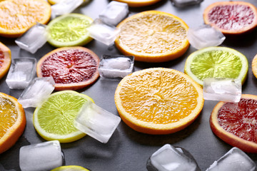 Juicy composition of citrus fruits and ice cubes on grunge background