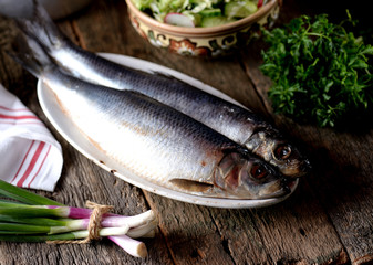 Salted herring with mashed potatoes and cucumber salad, radish and cabbage with olive oil on an old wooden background. Rustic style.