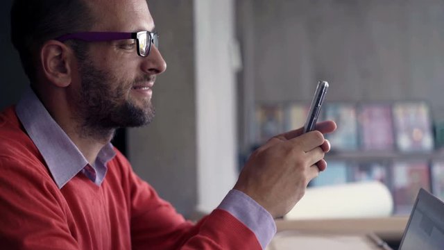 Businessman using smartphone by table in the office, 4K
