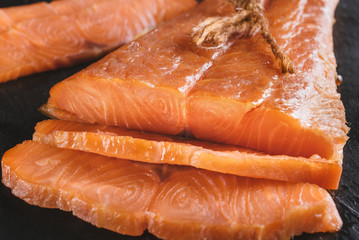 Smoked salmon fish on a slate board. Cutted slices of smoked salmon. Tasty smoked fillet of red fish