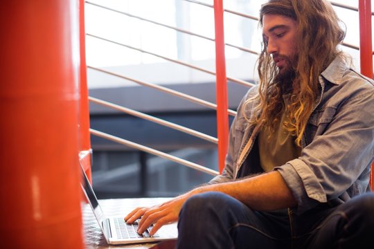 Executive using laptop on staircase