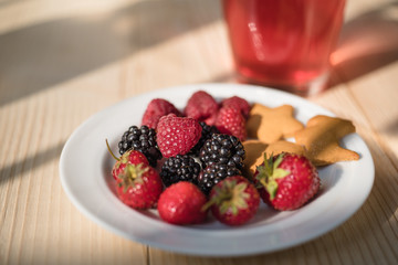Rustic healthy breakfast with blueberry, raspberry, crackers and juice in a glass on a wooden table. Healthy breakfast with vital vitamins.
