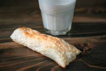 Rustic healthy breakfast with small loaf and yoghurt in a glass on a wooden table. Healthy breakfast with vital vitamins. Sunlight shines through the frame of a window. 