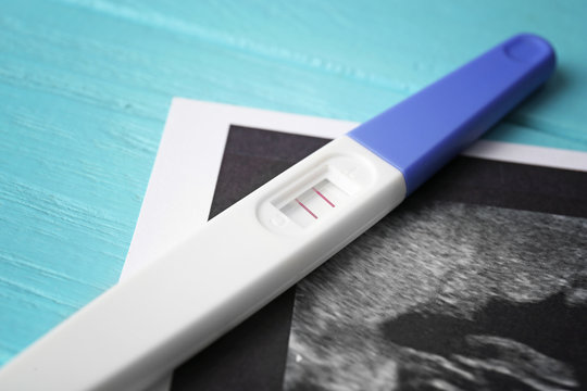Ultrasound photo and pregnancy test on blue wooden background