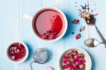 Herbal tea and dry roses on blue colored table