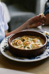 Person eating raviolis with gratin cheese, in restaurant