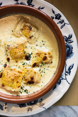 Person eating raviolis with gratin cheese, in restaurant
