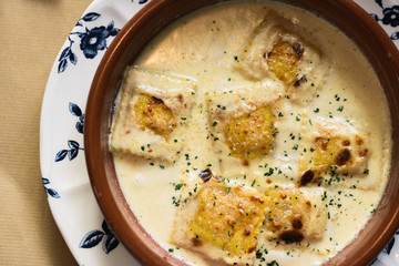 Person eating raviolis with gratin cheese, in restaurant