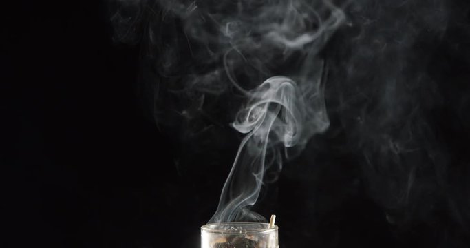 Wisps smoke billow and swirl in slow motion on black background
