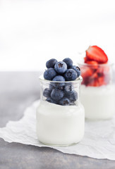Delicious plain yogurt with fresh blueberry and strawberry in a glass jars