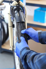 Wymiana opony w rowerze. Serwisant naprawia rower w serwisie rowerowym. - obrazy, fototapety, plakaty