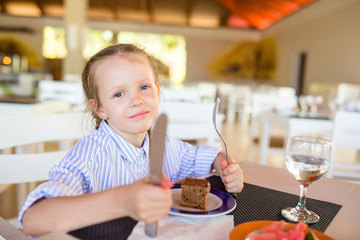 Adorable little girl having breakfast at outdoor cafe