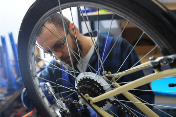 Konserwacja roweru. Mechanik w serwisie rowerowym czyści rower sprężonym powietrzem.
