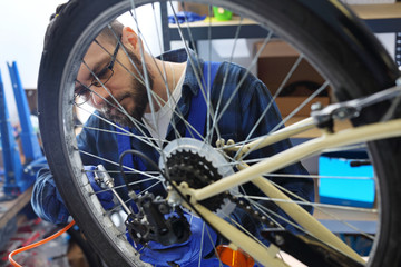 Serwis rowerowy. Mechanik w serwisie rowerowym czyści rower sprężonym powietrzem. - obrazy, fototapety, plakaty