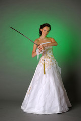 Girl in a wedding dress with a sword on the green background