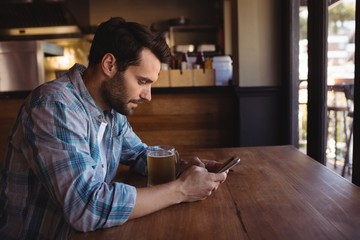 Man using mobile phone while having beer
