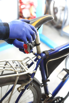Serwis rowerowy, wymiana siodła. Mężczyzna, pracownik serwisu rowerowego montuje nowe siodło rowerowe.