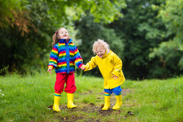 Kids play in rain and puddle in autumn