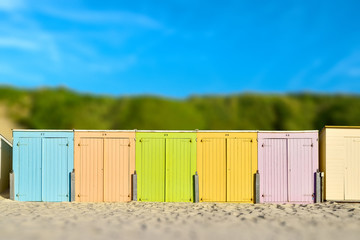 Naklejka premium On the Beach by the Sea - beautiful colorful beach huts on a sandy beach on a sunny day - miniature effect