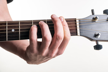The guitarist's hand clamps the chord Fm on the guitar, on a white background. Horizontal frame