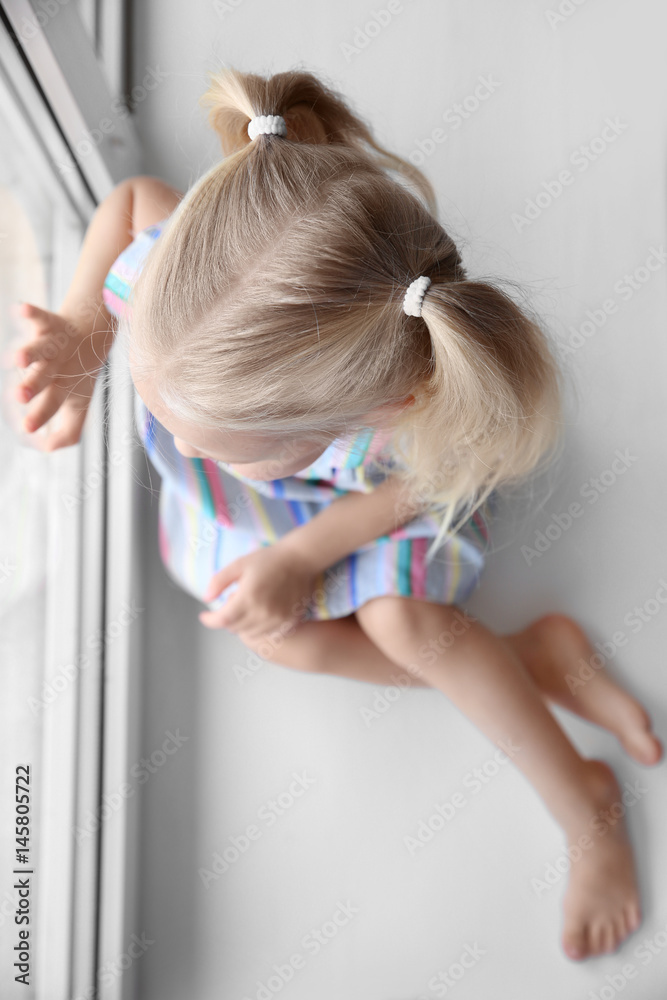 Poster cute little girl sitting on windowsill