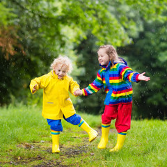 Kids play in rain and puddle in autumn