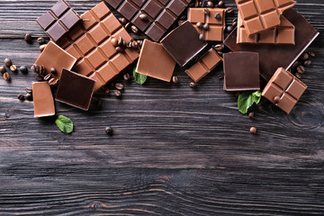 Chopped chocolate bars with coffee beans on wooden background