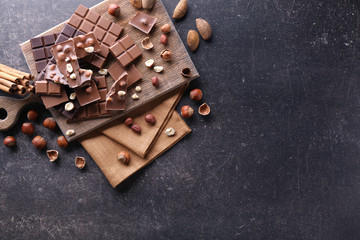 Chopped chocolate bars with nuts on gray background