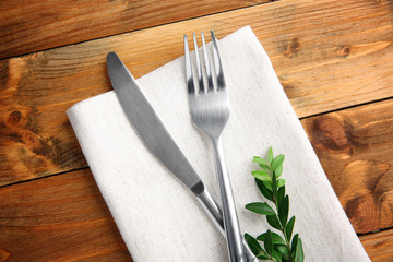 Table setting with silver cutlery and napkin on wooden background - obrazy, fototapety, plakaty