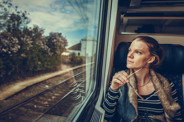The young woman is on the train and watches through the window on the outside