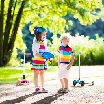 Kids riding scooter in summer park.