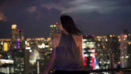 Young woman looking at the city on terrace during nigt, 4K
 - Powered by Adobe