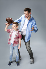 Father and son with rugby ball on color background