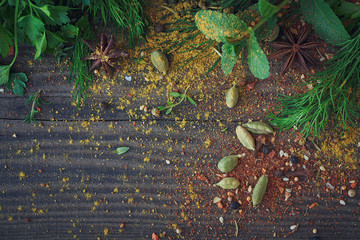Mix of fresh herbs and spices assortment on wooden background.