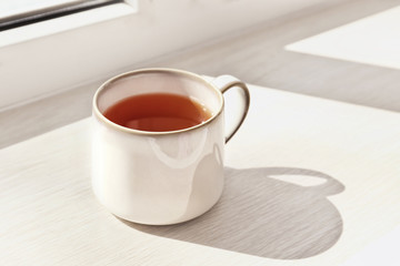 Cup of hot tea on window sill, closeup