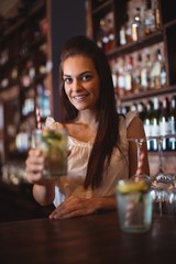 Portrait of female bar tender holding a glass of cocktail
