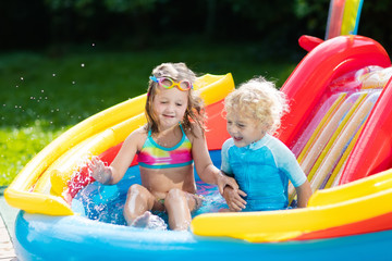 Fototapeta na wymiar Kids in garden swimming pool with slide