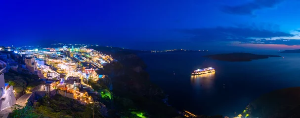 Amazing panorama of Fira, caldera, volcano of Santorini, Greece with cruise ships at night. Cloudy dramatic sky. © gatsi