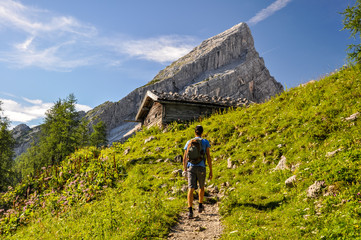 Young man hiking on a pathway up to Watzmann Mountain (2713m). In the background you can see a...