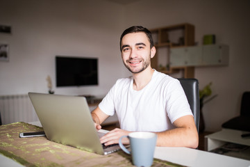 Portrait of young man using laptop while having breakfast in the morning