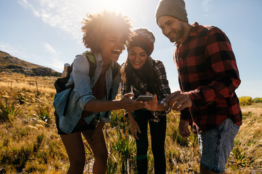 Group of hikers looking at pictures on phone and laughing