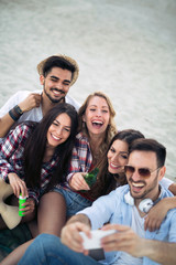 Happy young group of people taking selfies on beach