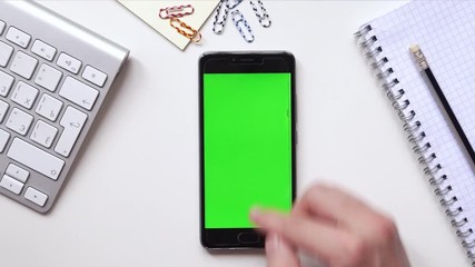 Businessman Using Mobile Phone with Green Screen which Lying on the Table. Top view.
