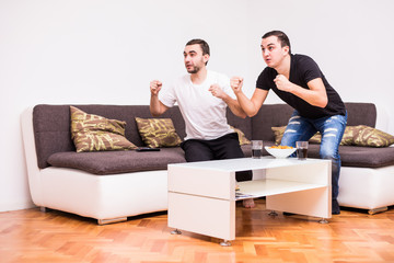 Two young men watching a football match on tv. Sport fans
